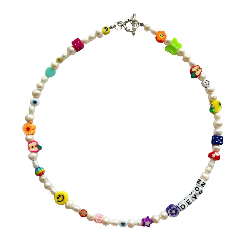 Collar de perlas con dijes de colores de flor, mariposa, manzana, hongo, dado y ojo turco, y letras blancas al frente