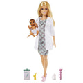 Muñeca doctora con bata blanca y vestido de mariposas, cargando un bebé, con estetoscopio, tablilla, mamila y aparatos de revisión